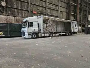 DAF tautliner van DTC met geperste recyclingbalen tijdens lossen bij verwerkingsbedrijf, transport door De Transport Compagnon.