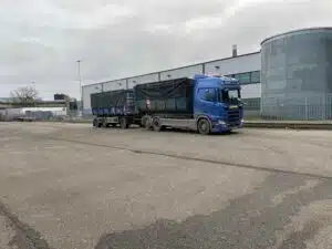 Scania containerauto met aanhangwagen van De Transportcompagnon op bedrijventerrein voor afvaltransport.