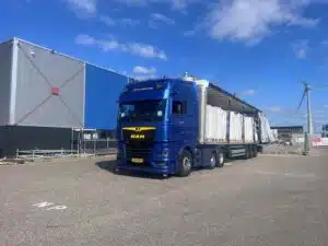 Blauwe MAN trekker van DTC Surhuisterveen met tautliner geladen met bigbags voor industrieel goederentransport.
