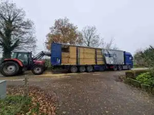 DTC tautliner wordt gelost met strobalen door tractor met voorlader, agrarisch transport door De Transport Compagnon.