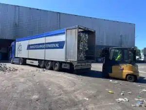 DTC schuifvloer trailer lost geperste plastic balen bij recyclingbedrijf, walking floor transport door De Transport Compagnon Surhuisterveen.