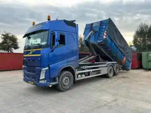 Blauwe Volvo FH containerauto met haakarmsysteem en container van De Transportcompagnon Surhuisterveen.